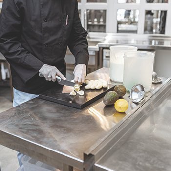 chef-using-commercial-stainless-steel-work-table-for-restaurants Chef using stainless steel worktable in the back of a restaurant.