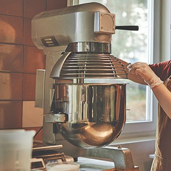 commercial-mixers-for-bakeries-and-restaurants Commercial stand mixer on countertop kneading dough.