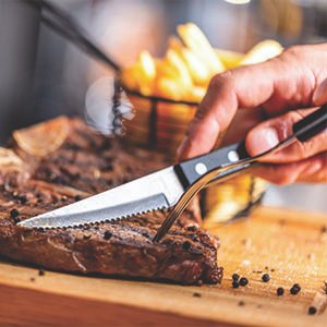 person using a steak knife to cut steak for a meal